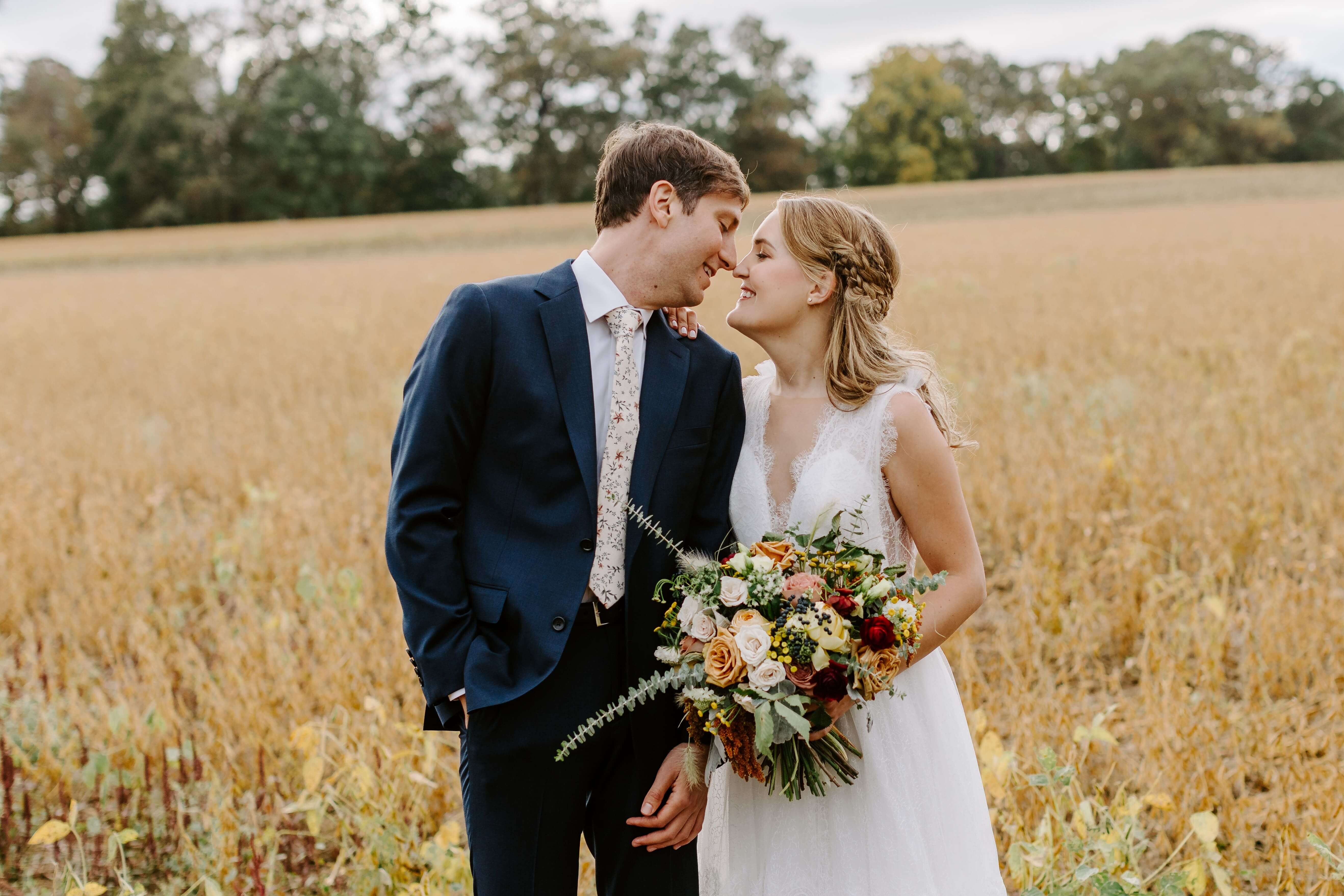 bride and groom about to kiss while in yellow field