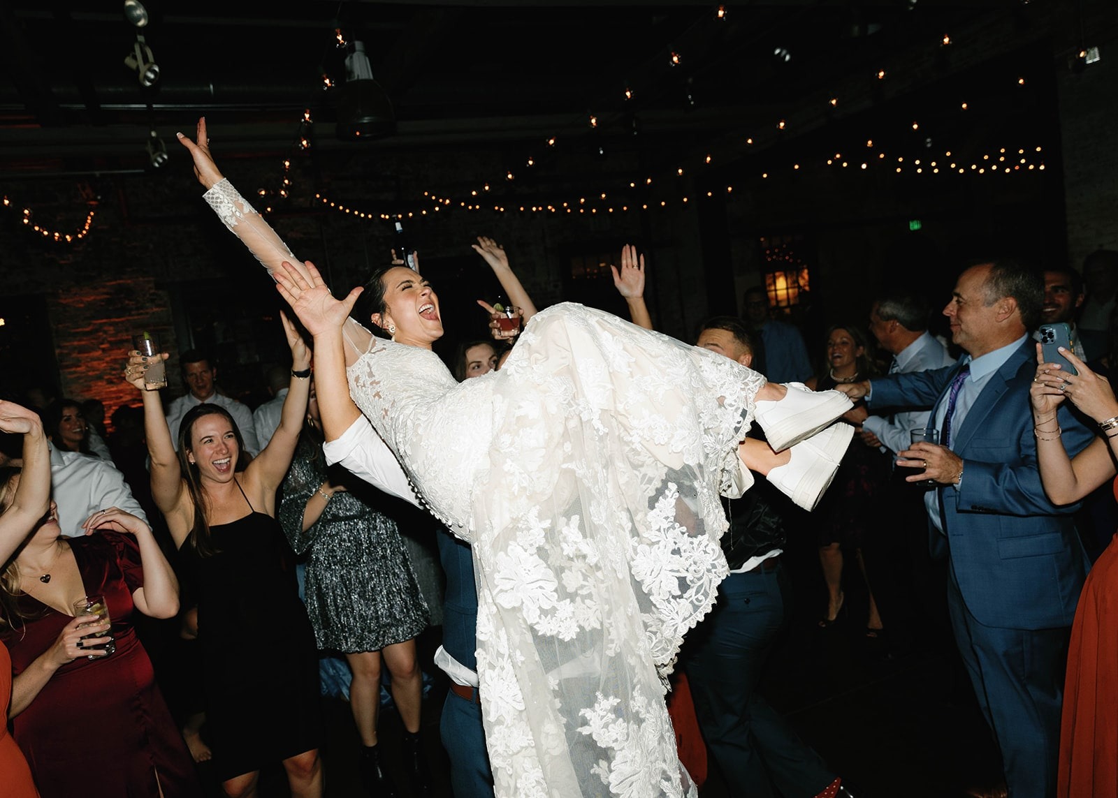 bride lifted up by guests on wedding dance floor