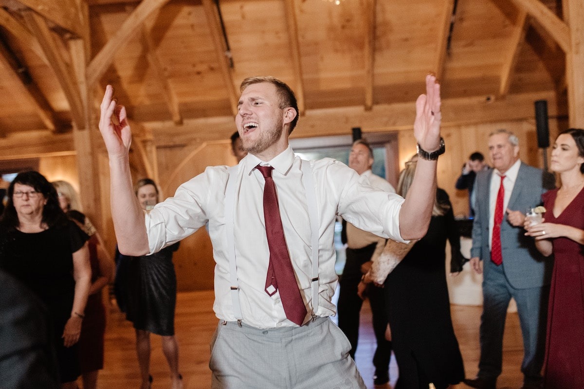 guy wearing a maroon tie dancing at wedding