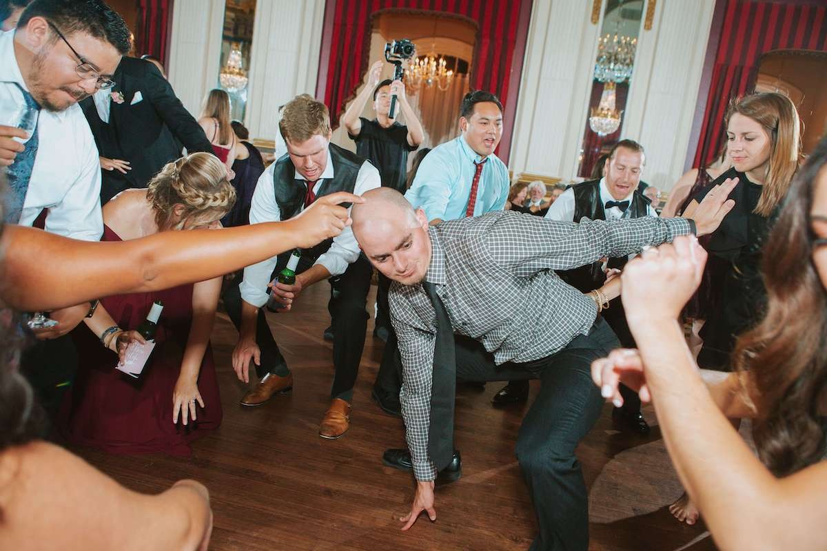 bald guy dancing bent over with hand braced on floor at wedding