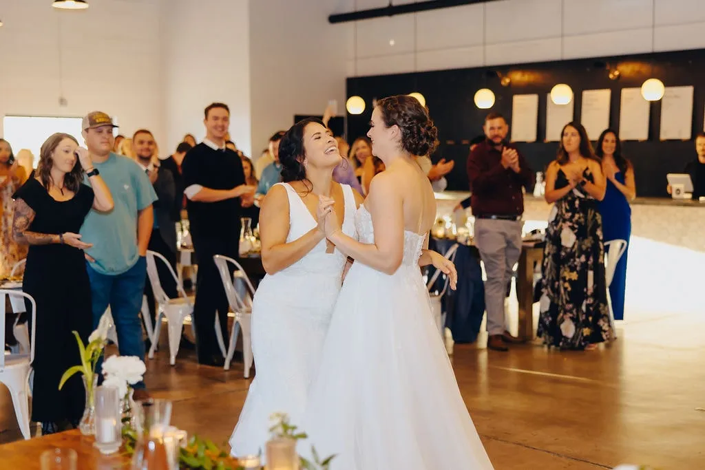 two bride first dance while guests watch