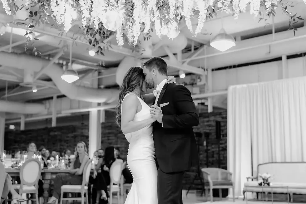 bride and groom dancing underneath a floral installation while guests watch from their seats