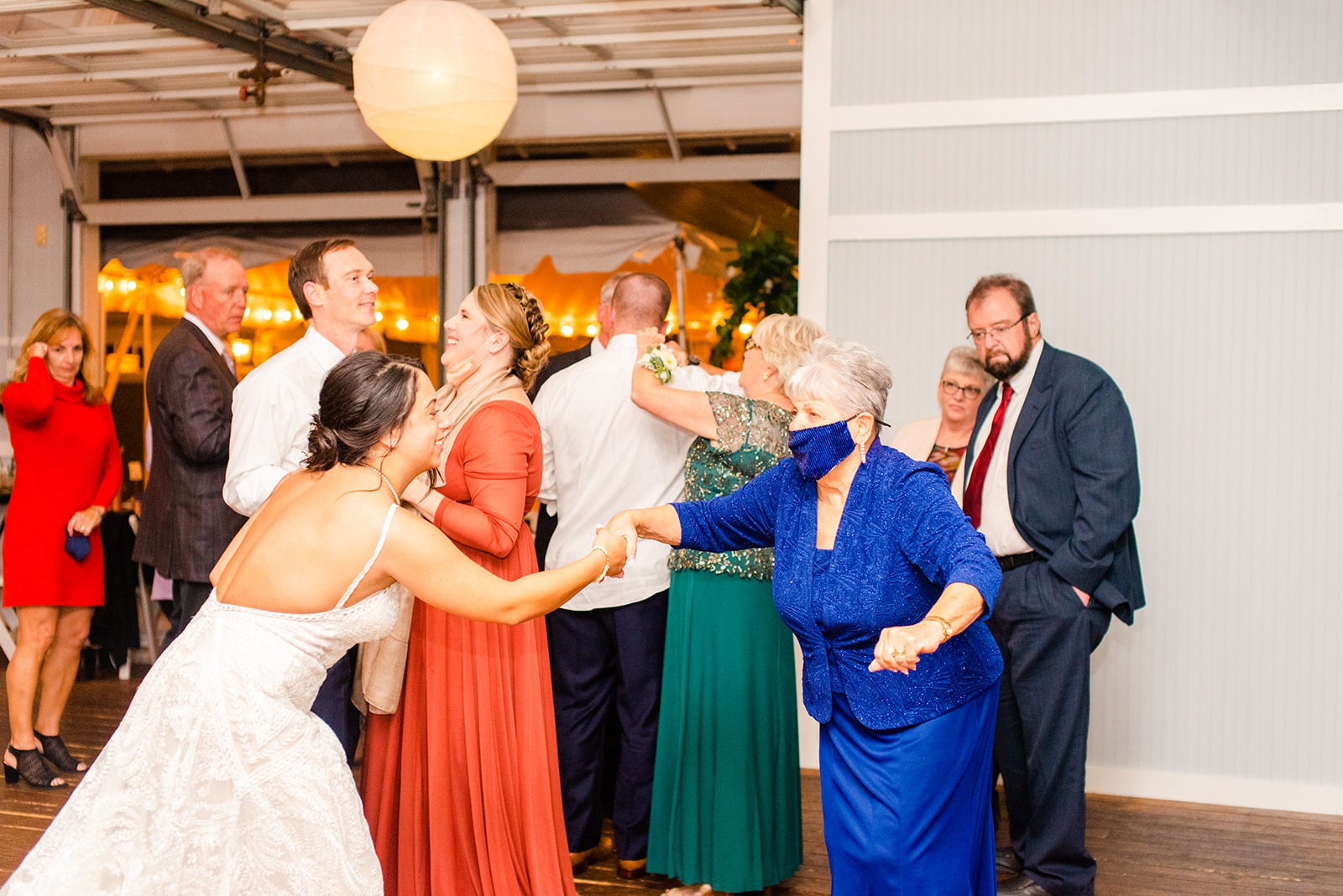 bride and older woman in blue dress and blue mask dance at wedding