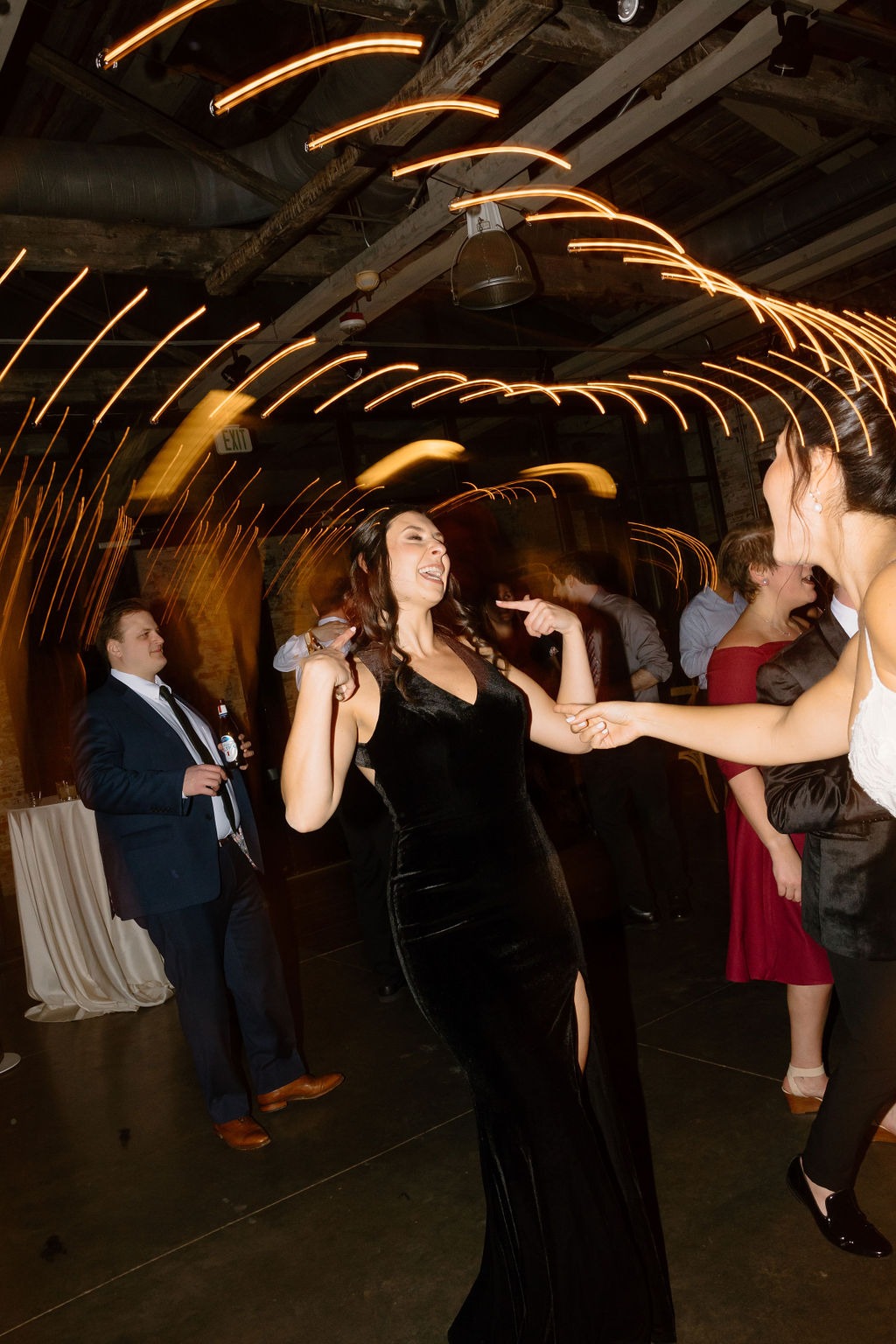 woman in black dress dancing with bride at wedding