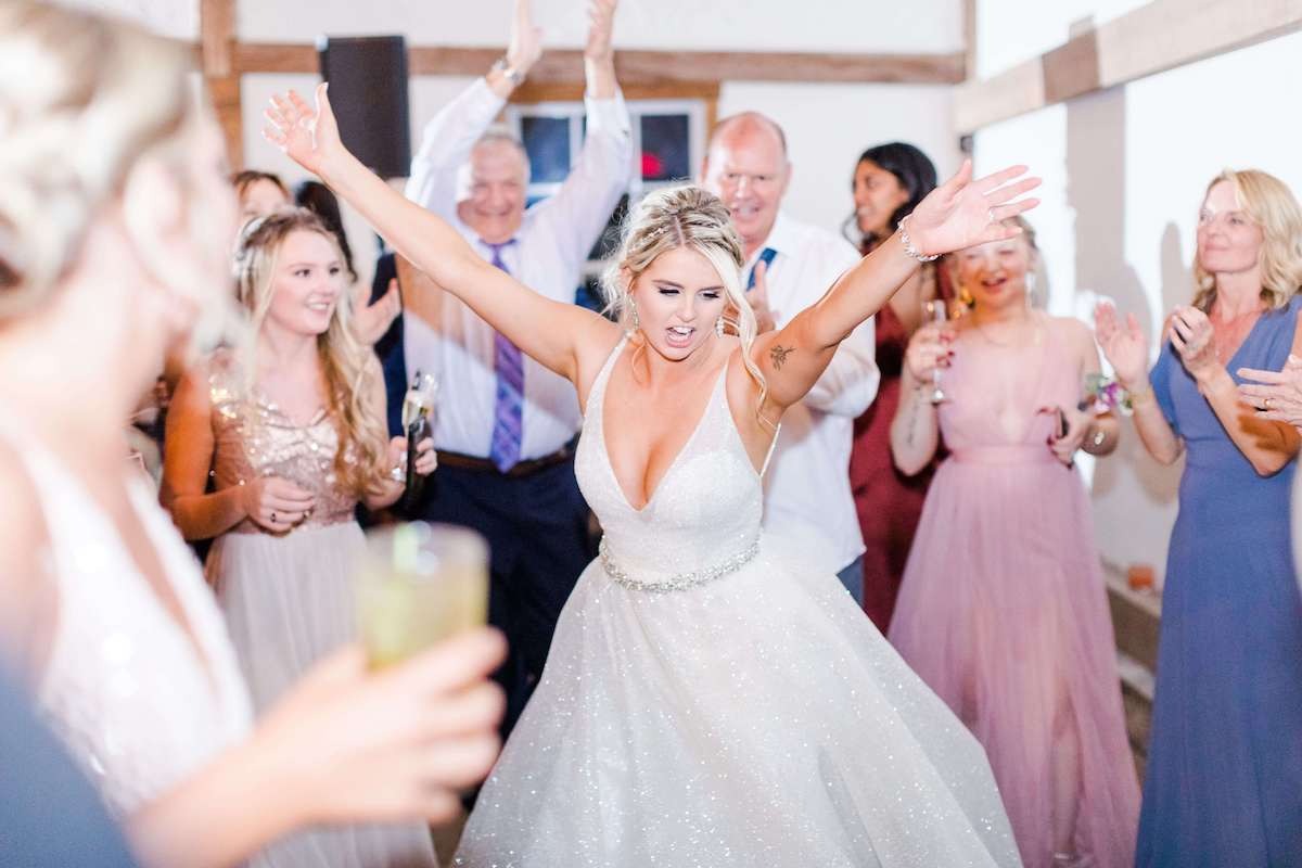bride dancing with hands up surrounded by women on dance floor