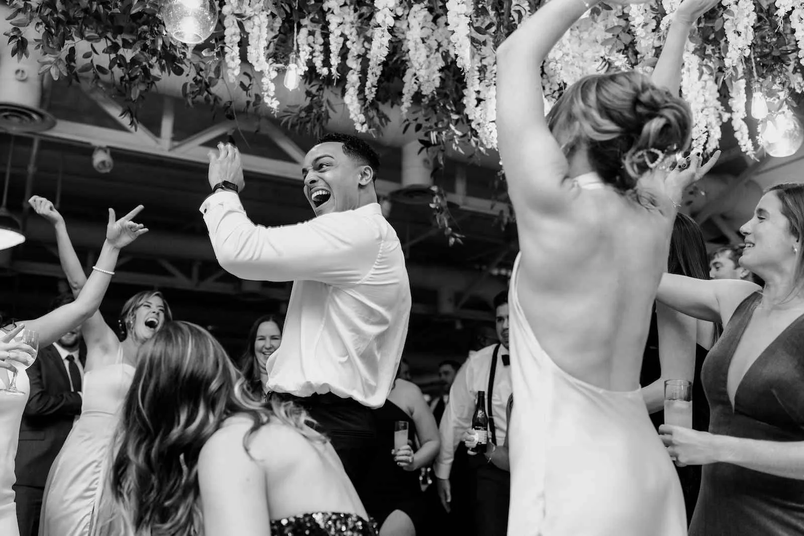 groomsman dancing with a smile while guests surround him with arms up