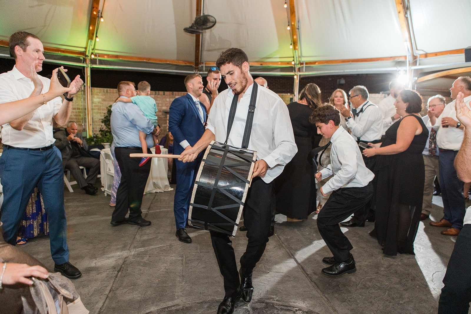 guy banging a portable drum while dancing at wedding