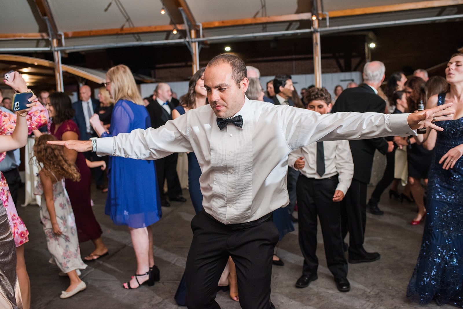 guy in bow tie dancing with arms outstretched at wedding