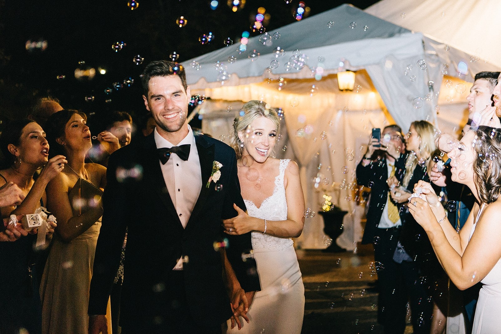 bride and groom exit wedding while guests blow bubbles