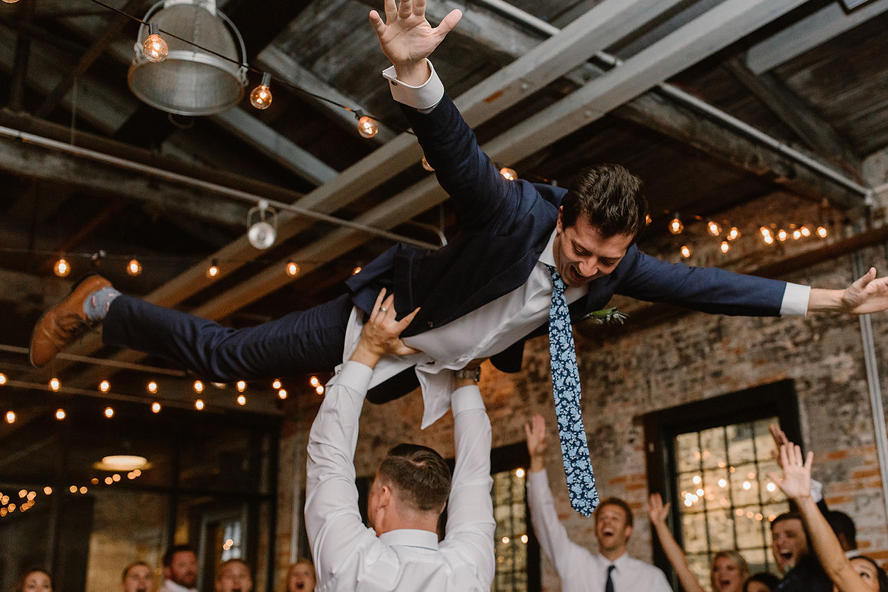 guy holds up groom overhead