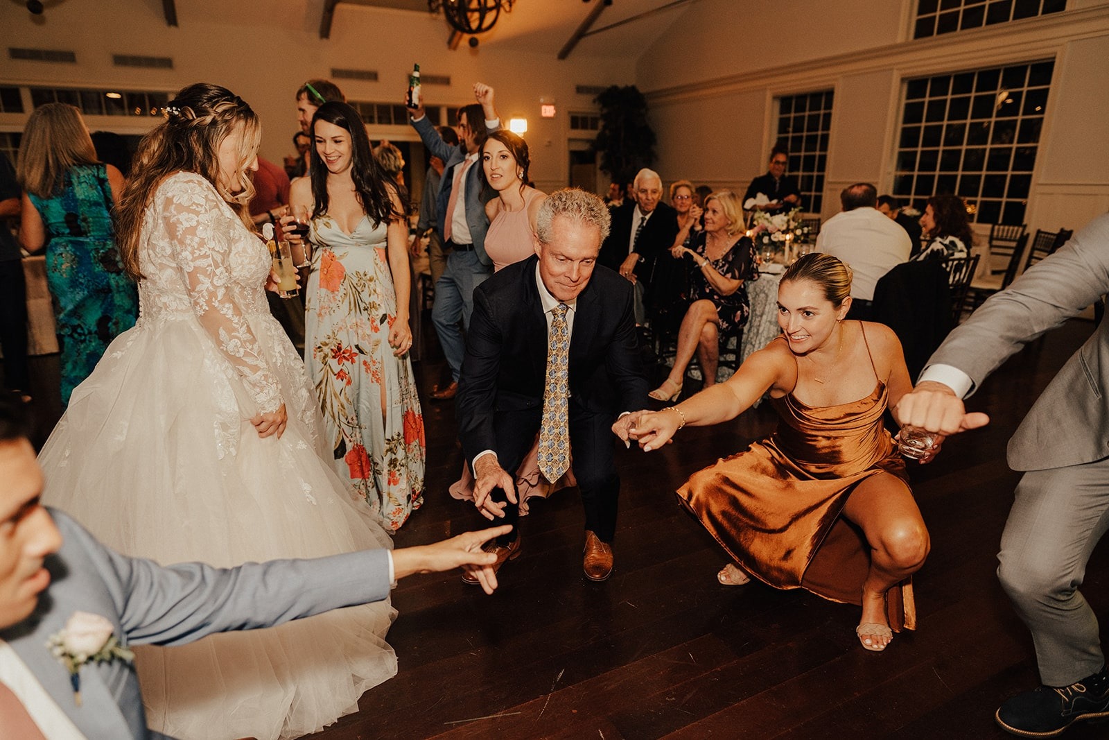 bridesmaid and groomsmen point at each other while crouched down on the dance floor