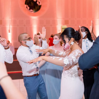 bride and groom dance with guests while wearing masks