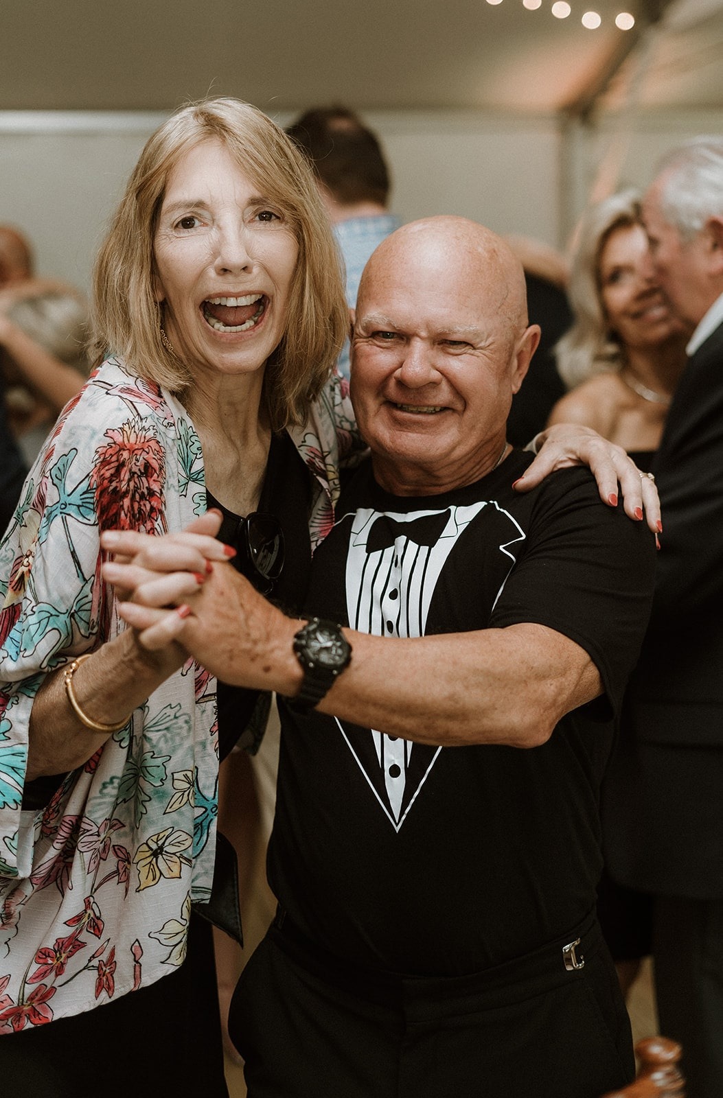 older man in tux shirt dancing with woman