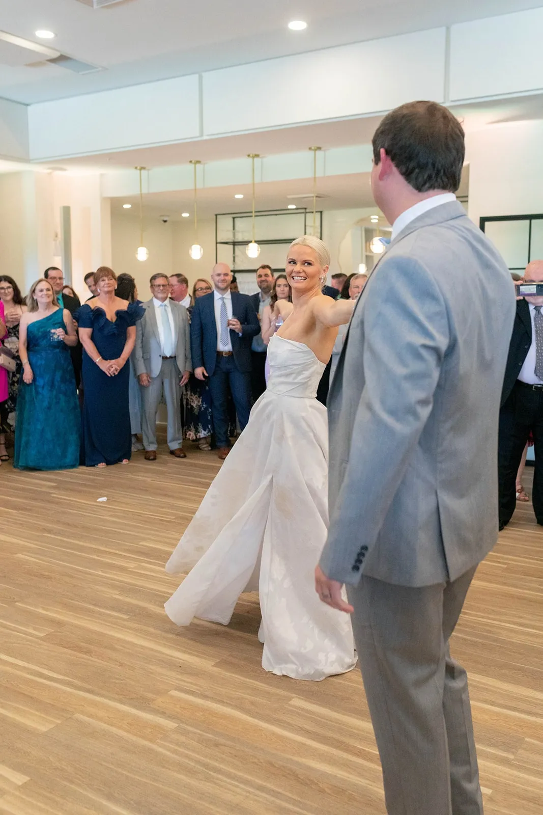 bride and groom first dance while guests watch