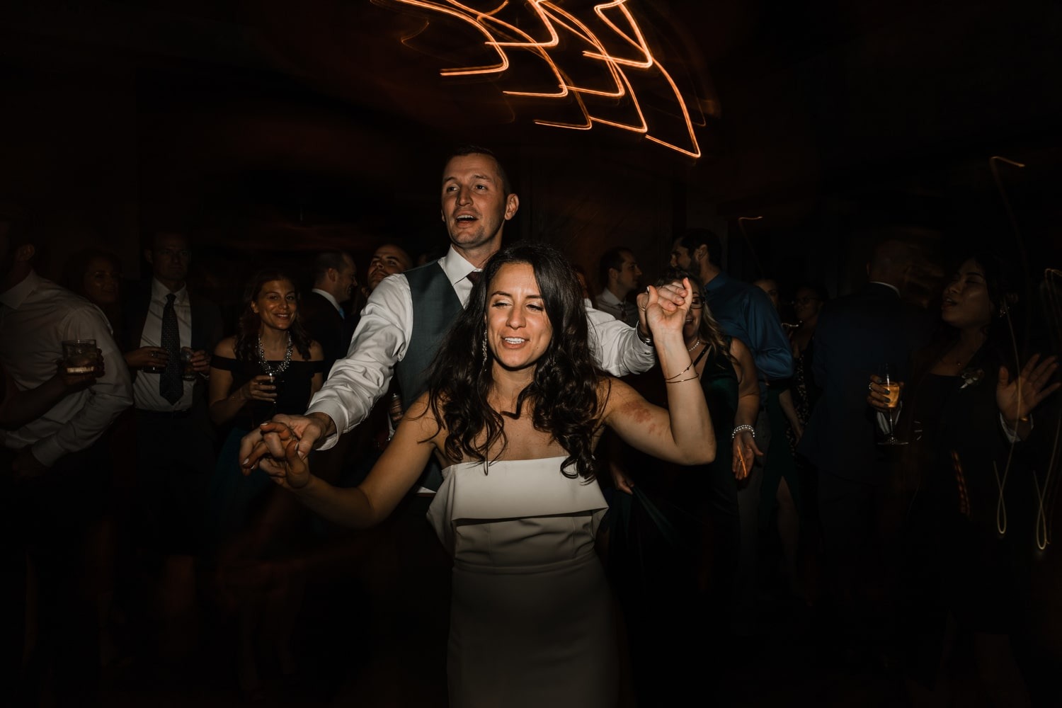 bride dancing in front on groom while holding his hands