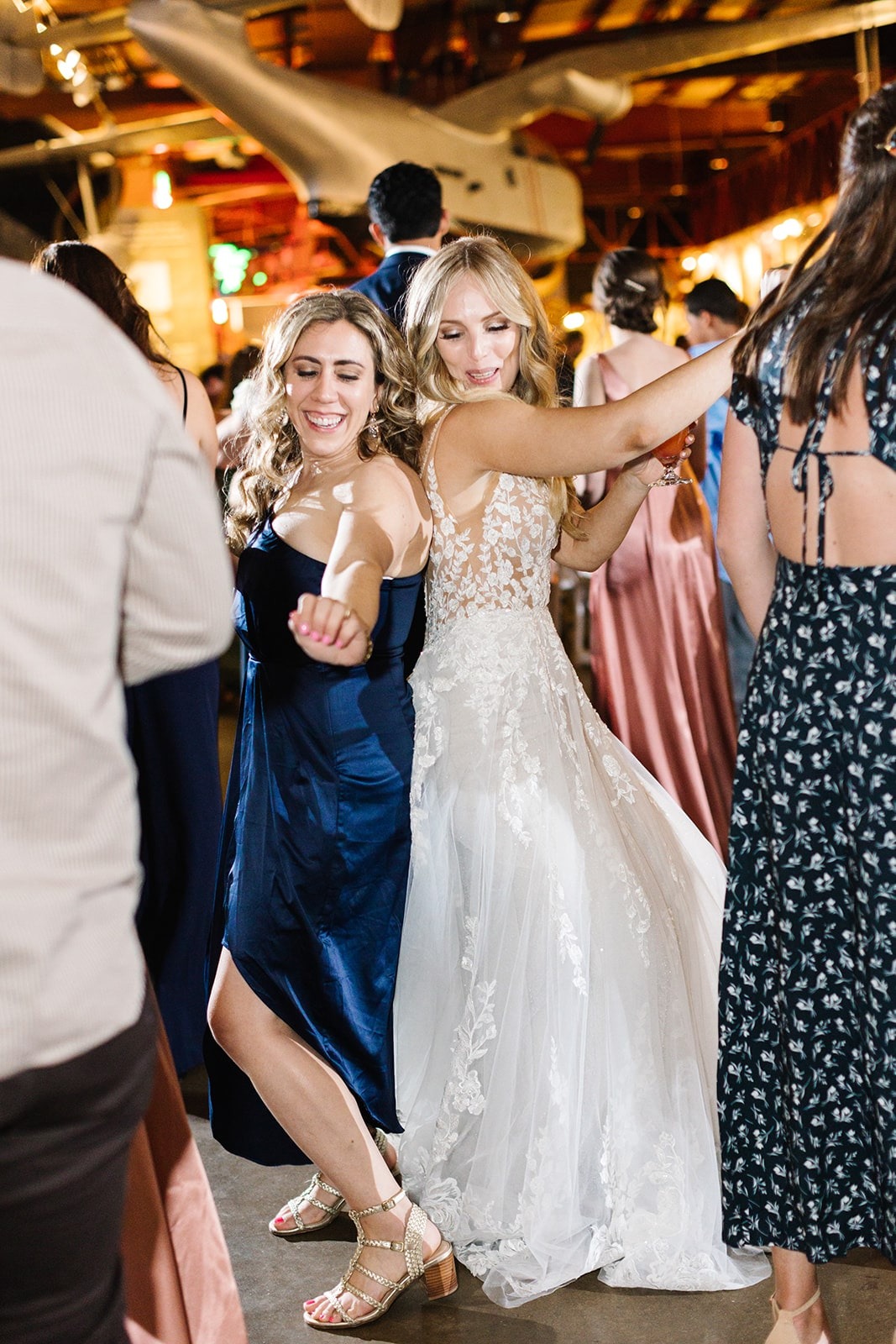 bride and woman in navy dress dancing back to back