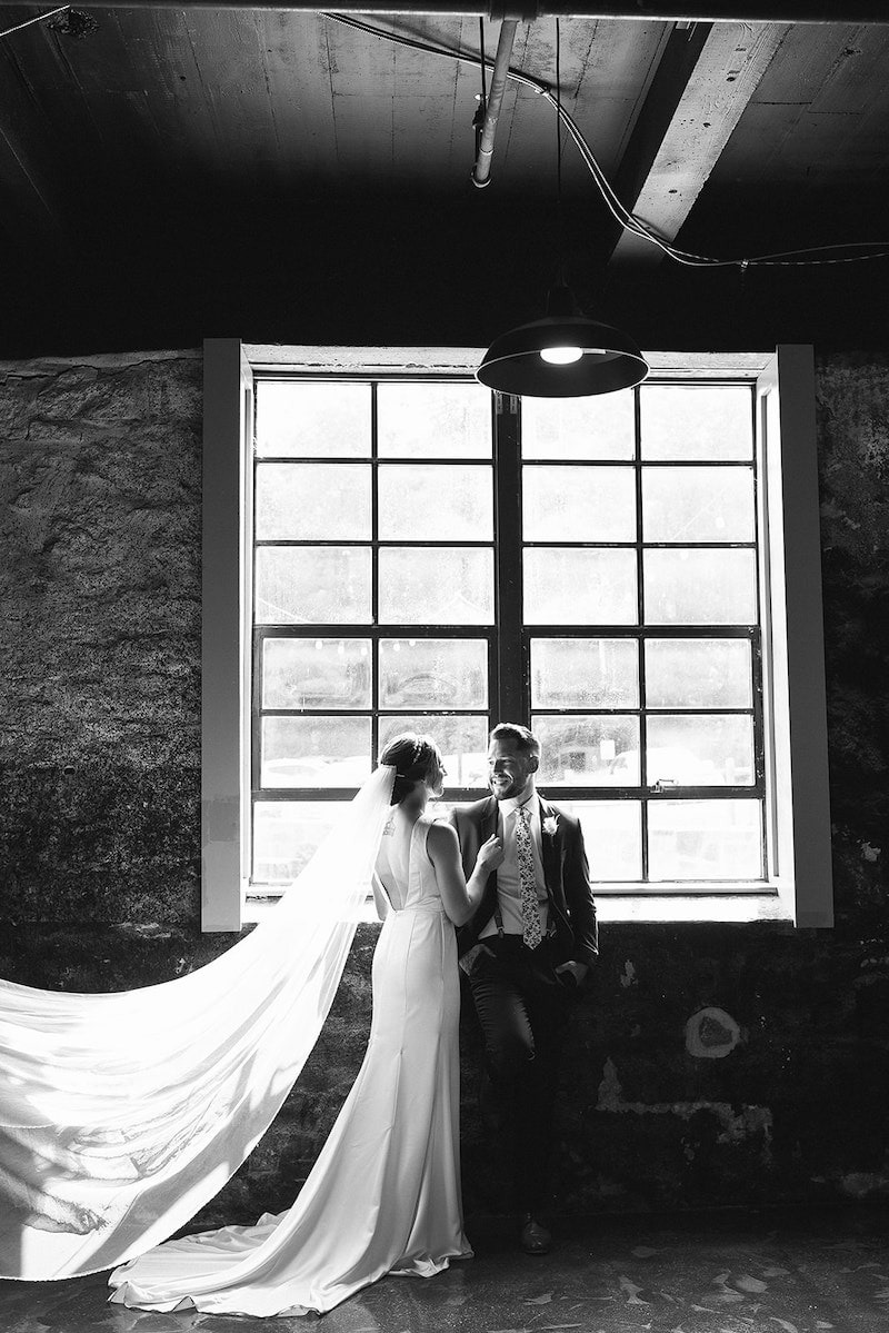 bride and groom pose in front of old window