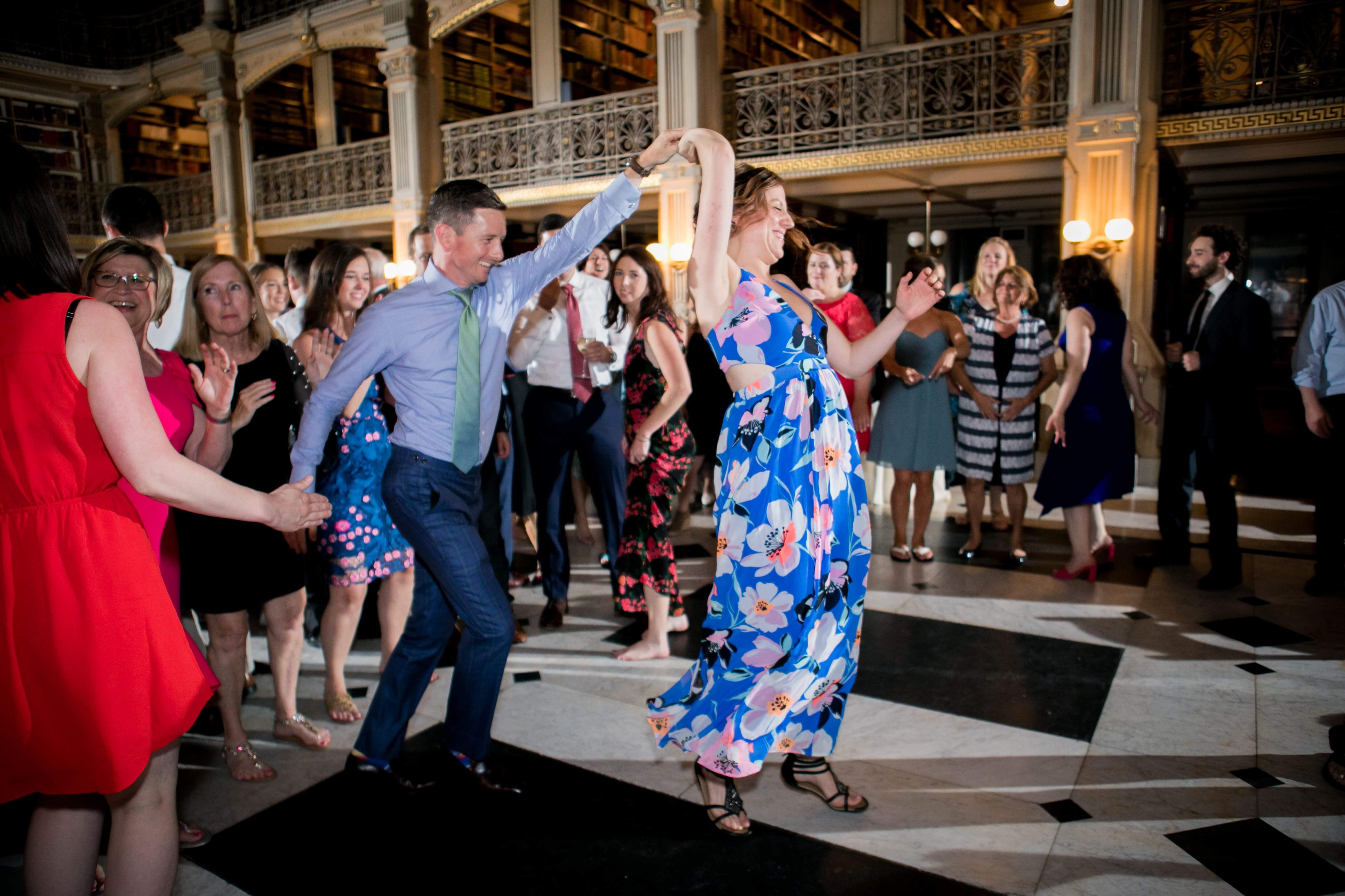 woman in floral dress being spun by man at wedding