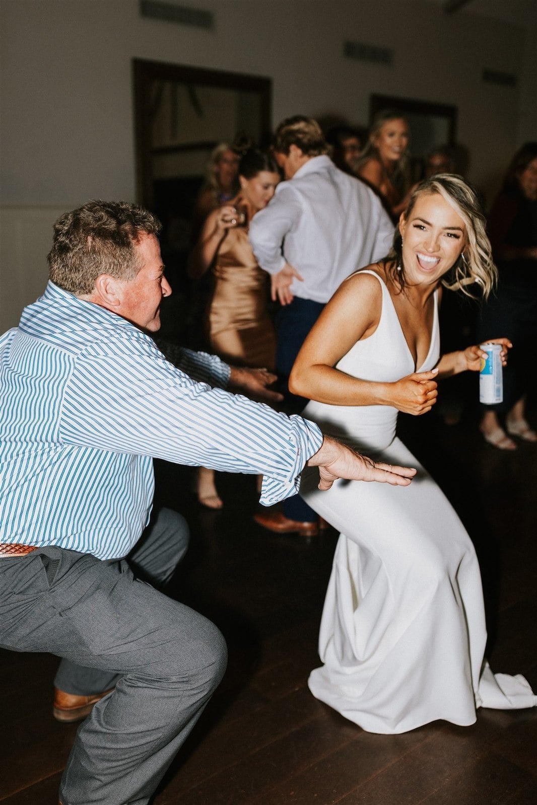 bride and guy in blue striped shirt dance