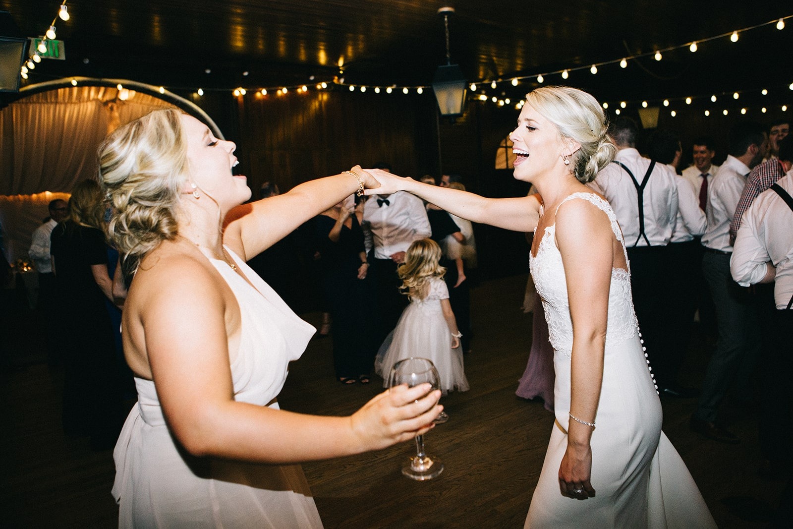 bride and bridesmaid dance while holding hands