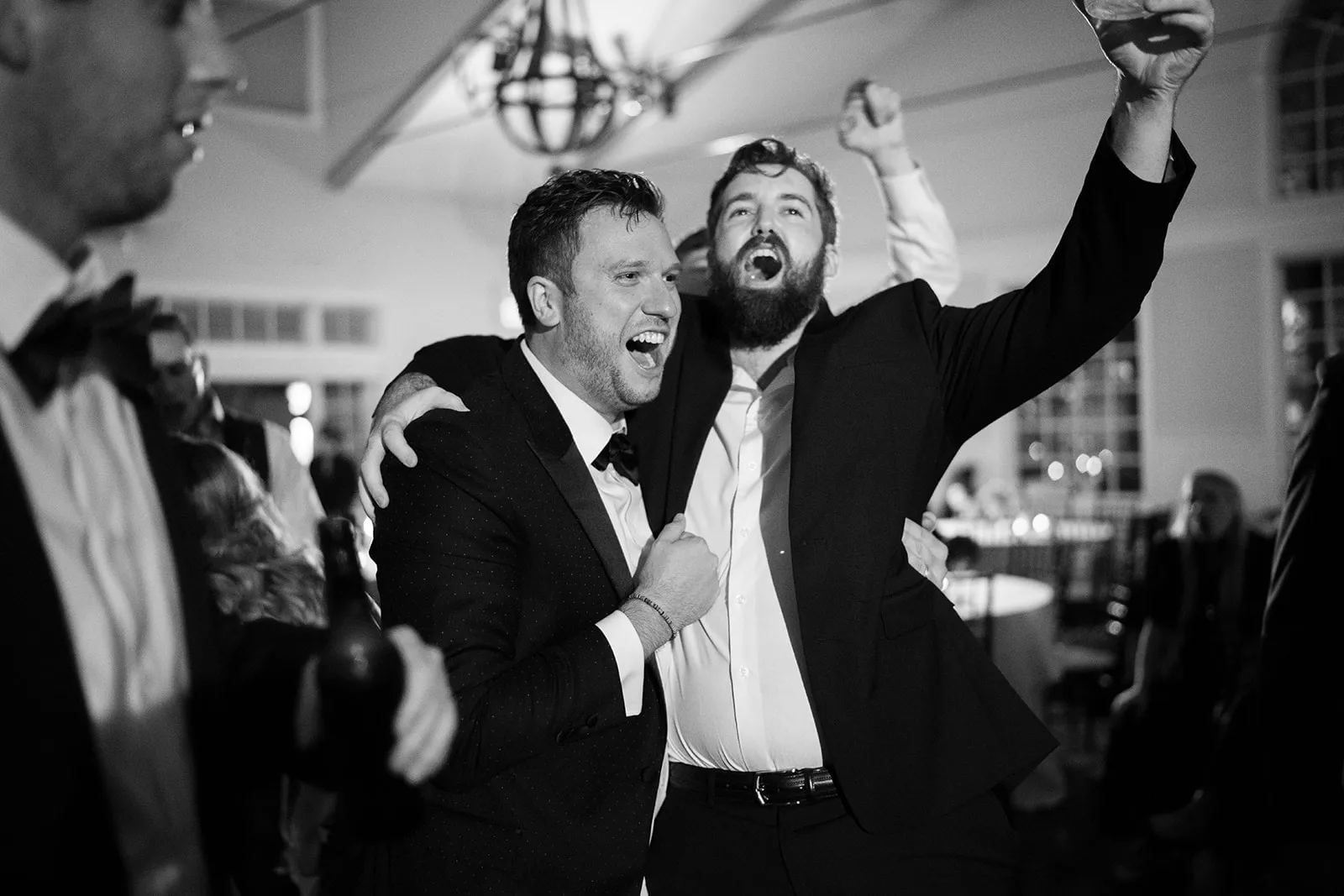 two guys laughing and singing at wedding