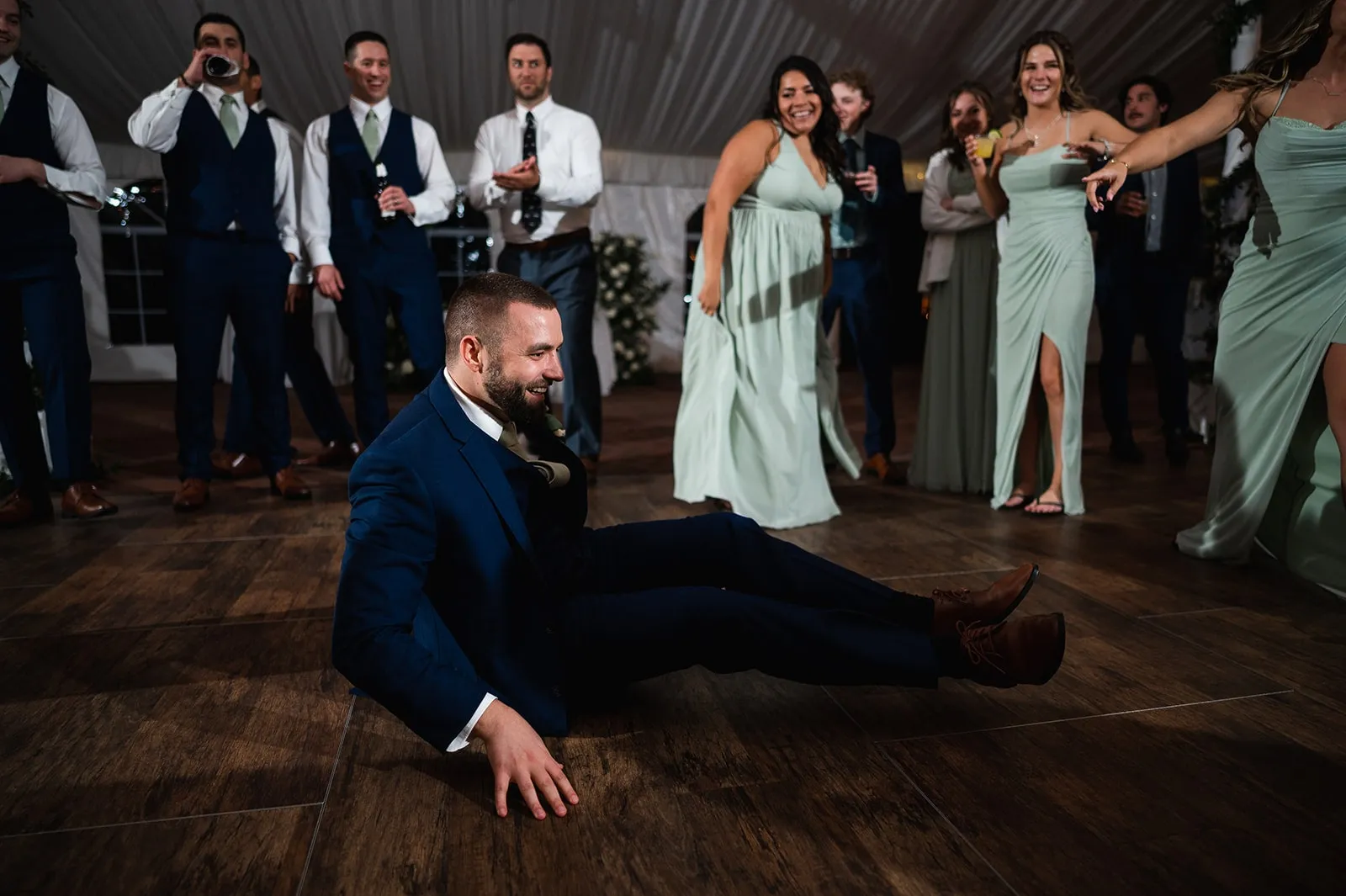 groom sitting on the dance floor while guests watch