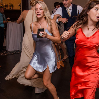 woman in blue dress and woman in red dress dancing at wedding
