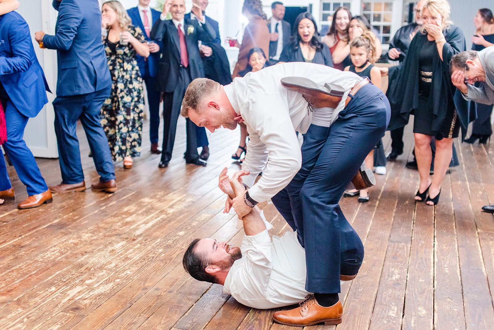 two guys dancing at wedding while one picks up the other from the floor