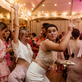 bride eating cake while woman is dancing behind her