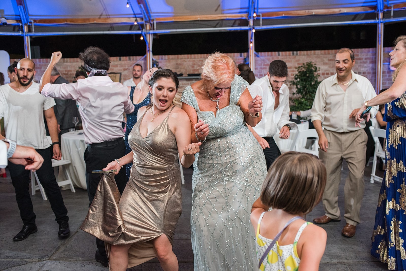 woman in gold dress dancing next to woman in silver dress at wedding