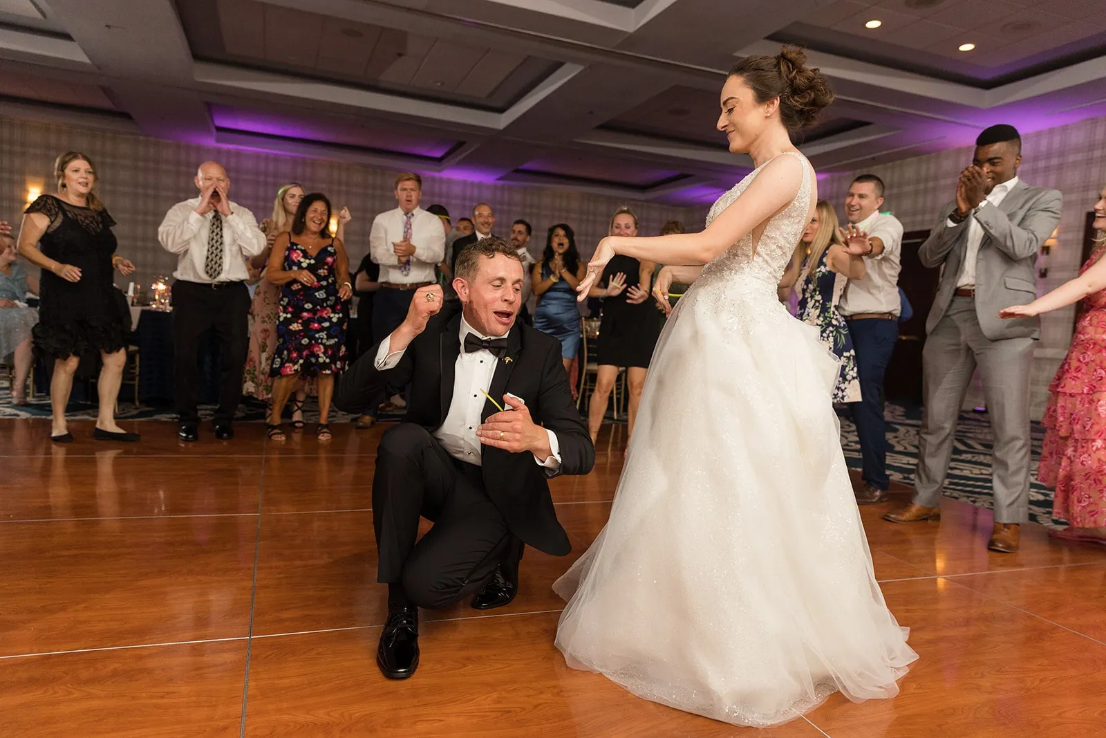 groom kneeling on floor with bride dancing