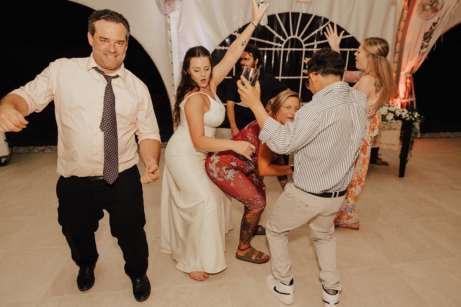 bride dances behind woman in red dress