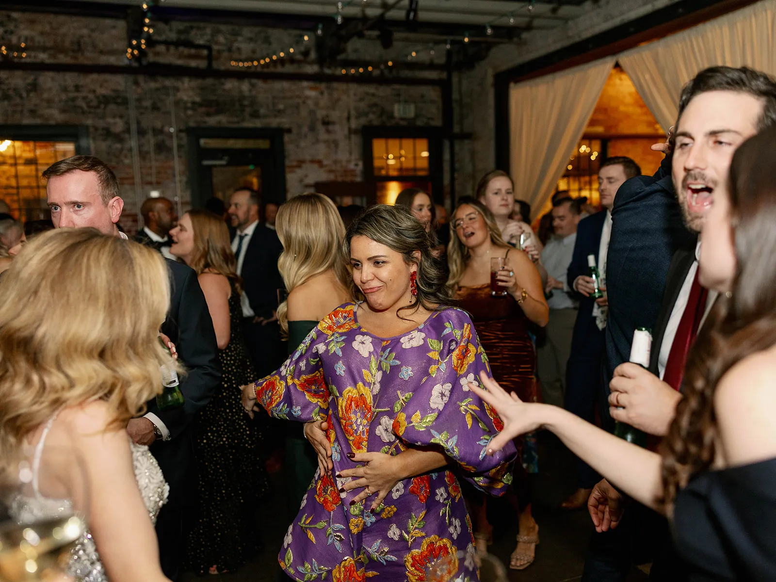 woman in floral dress dancing with guests at wedding