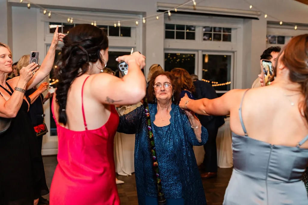 older woman in blue dress dancing with women at wedding