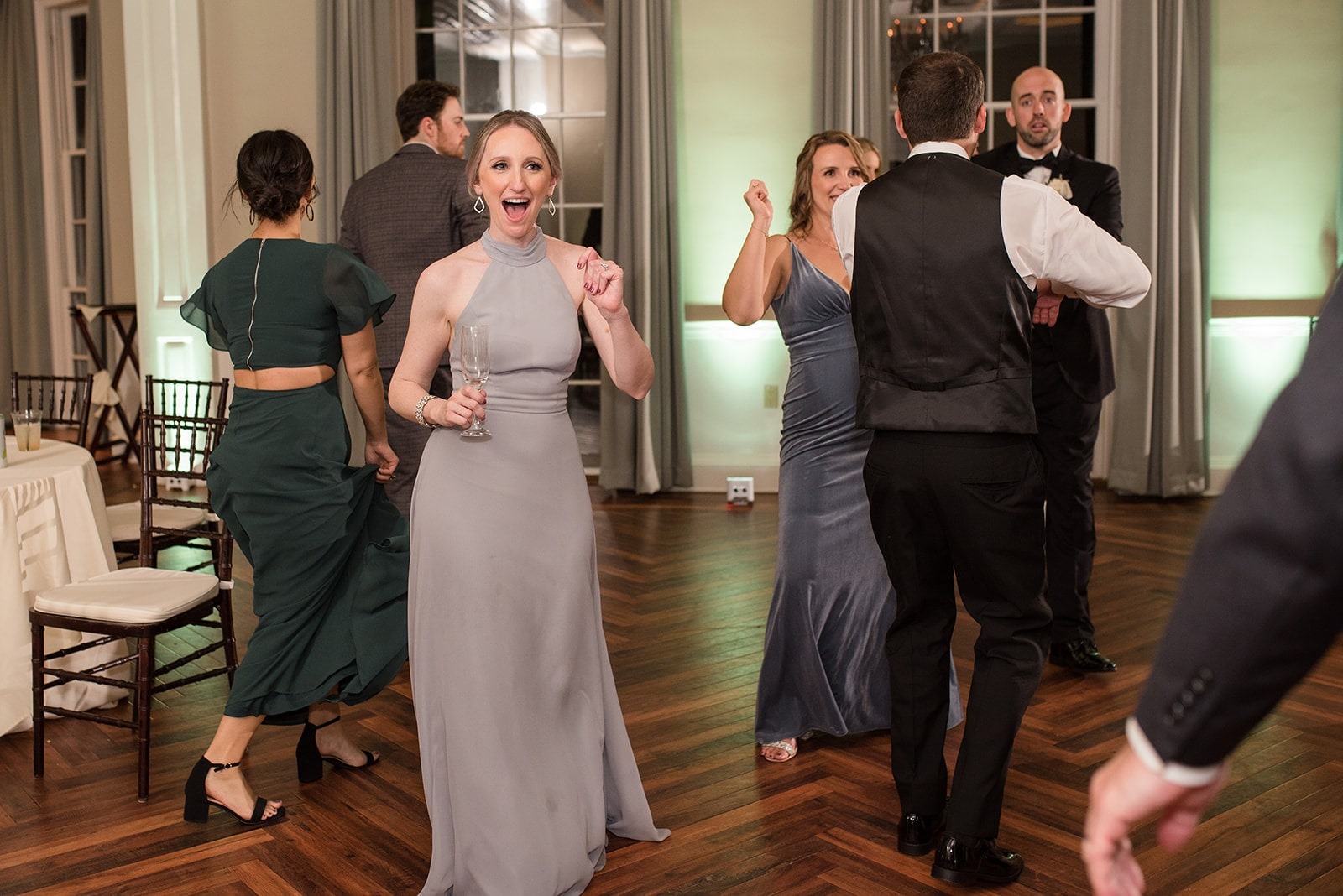 bridesmaid in long grey dress dancing with guests at wedding