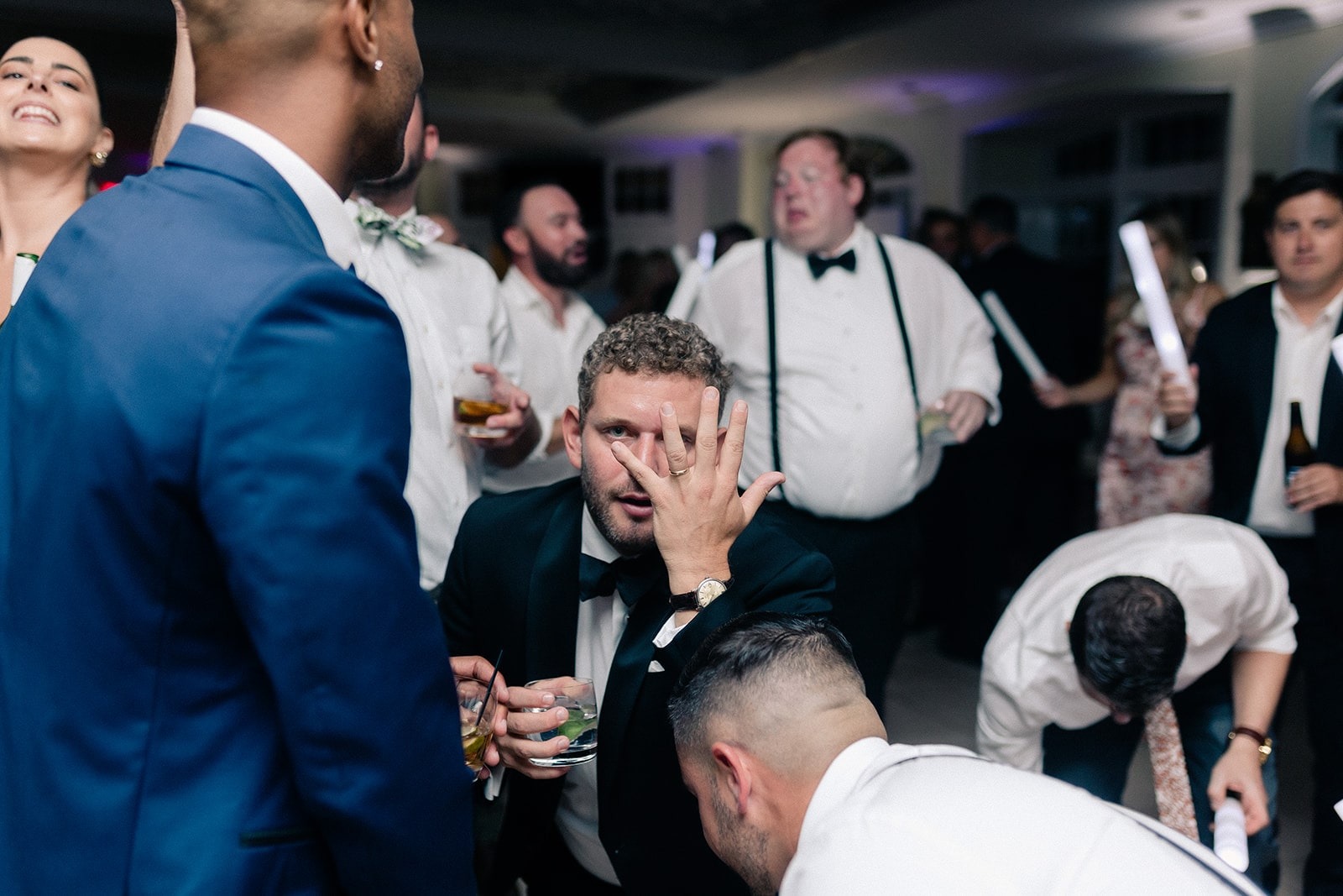 groomsman in tux dancing with hand in front of face
