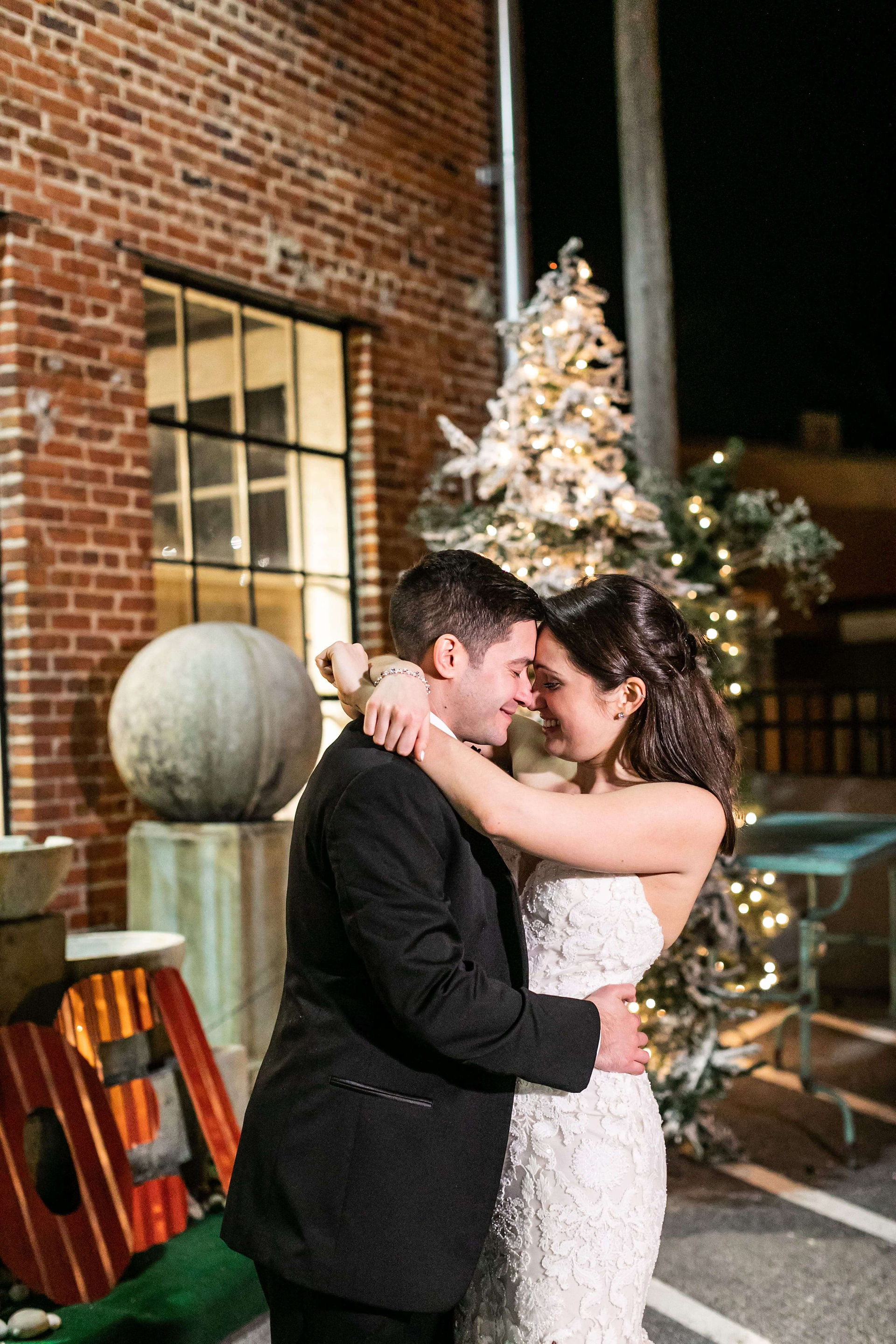 bride and groom pose outside brick building at night