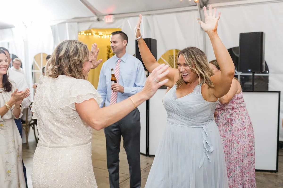 woman in light blue dress dancing at wedding with hands up