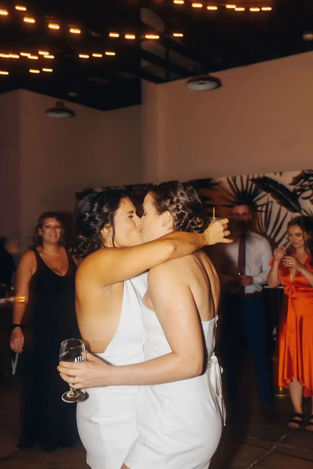 brides kissing each other while guests dance around them