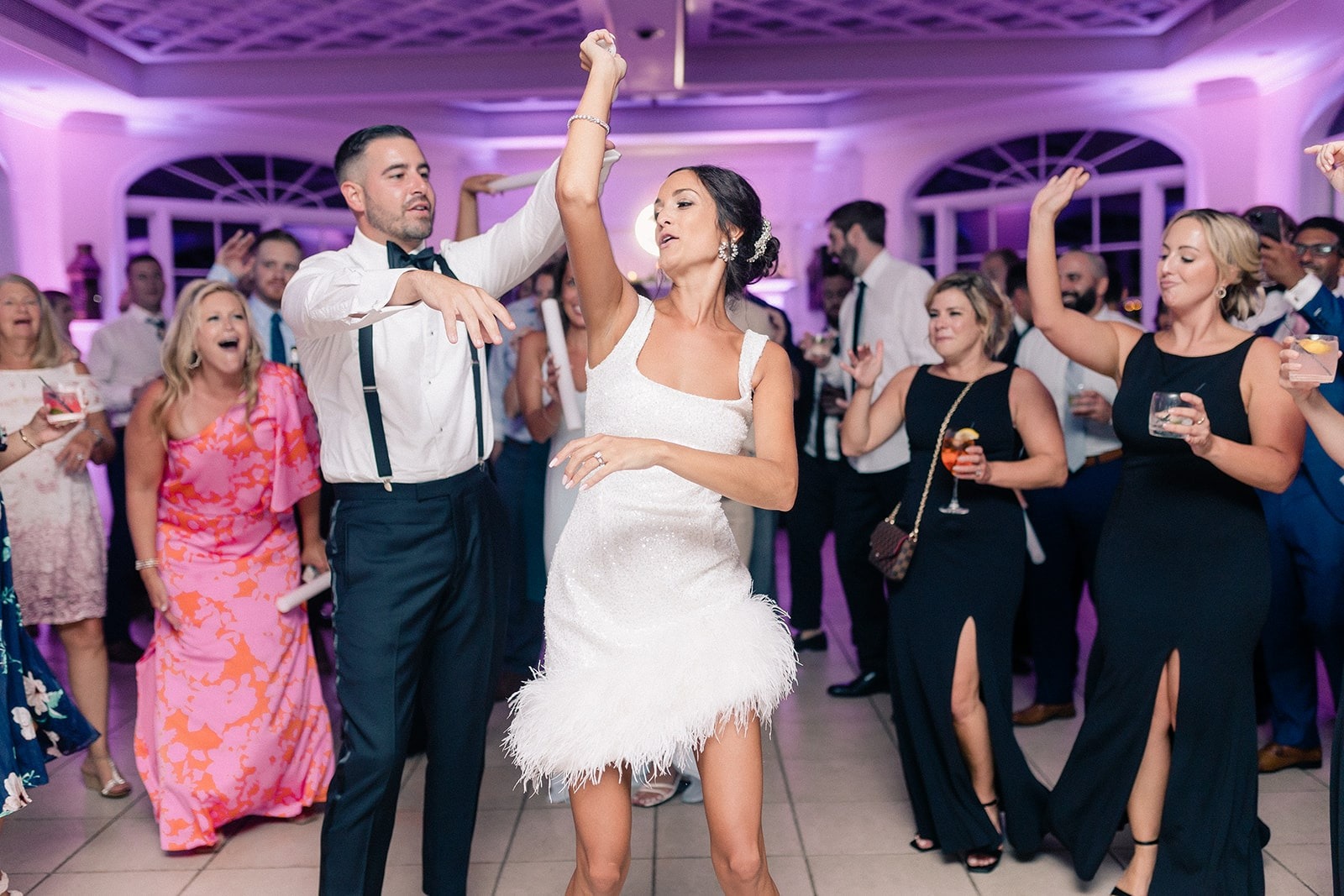 bride and groom dance while guests surround them