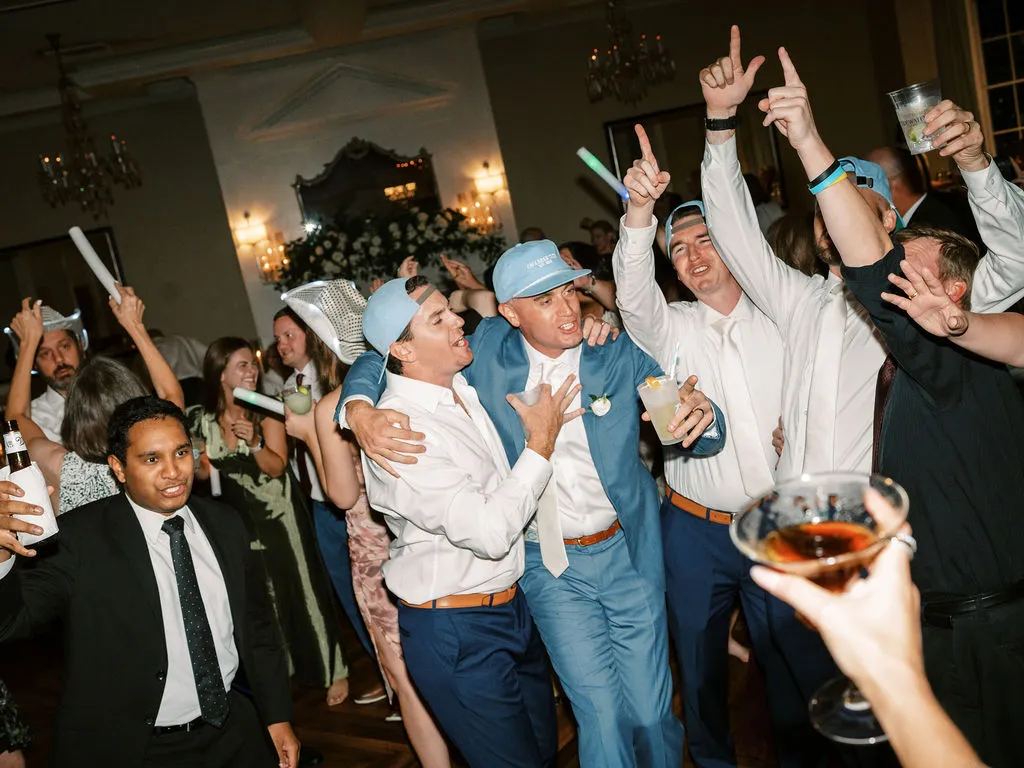 wedding guests wearing baseball caps dancing