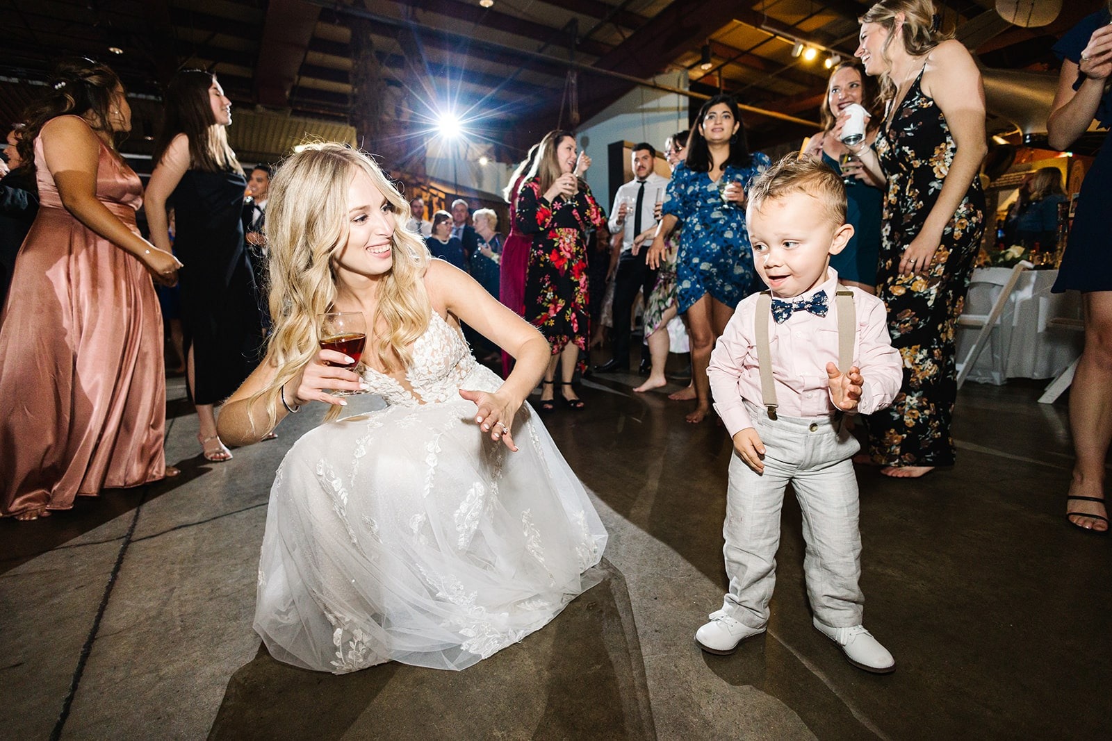 bride dancing low next to young boy in suspenders