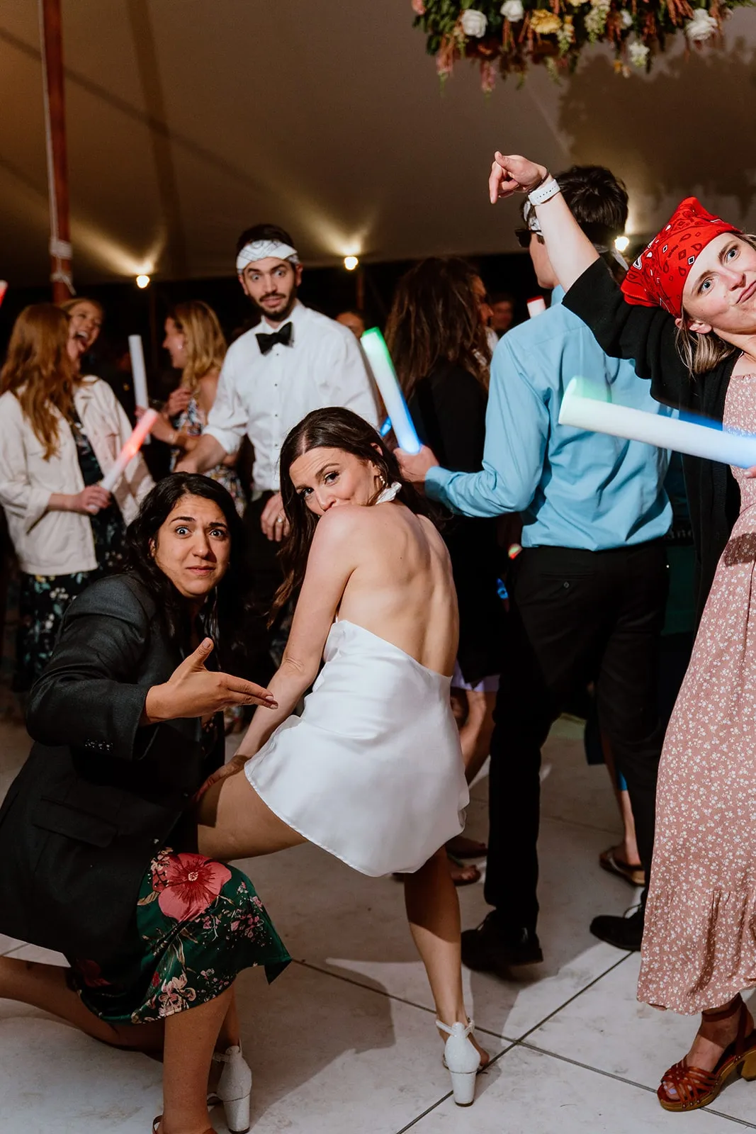 bride dancing low while friend pointing for the camera at her body