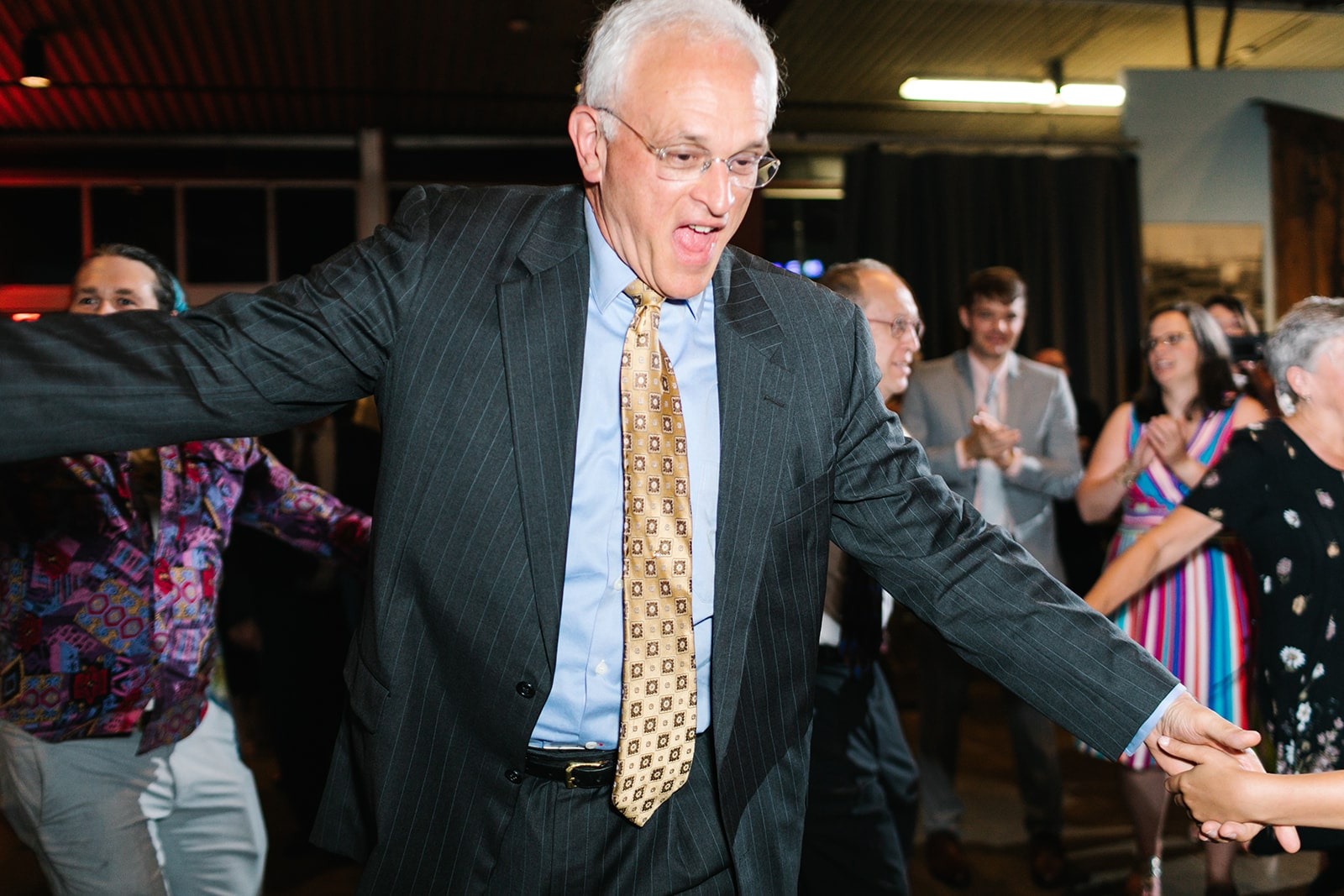 older man in suit and tie dancing at wedding