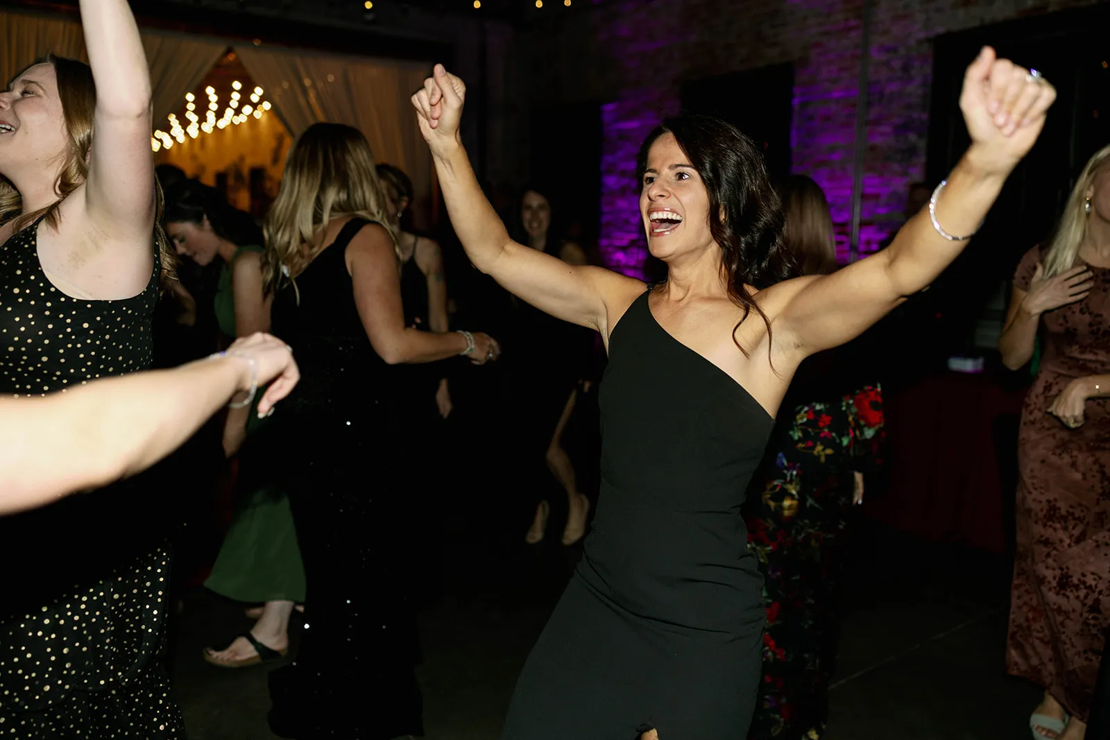 woman in black dress dancing with hands up