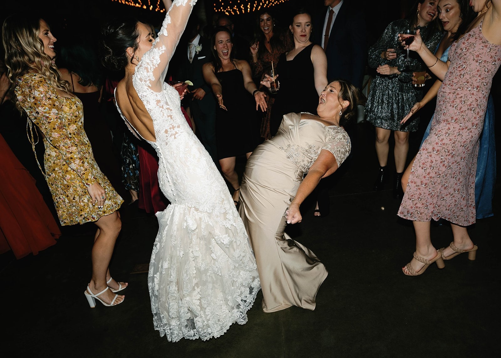bride and mother dancing and leaning backwards away from each other at wedding