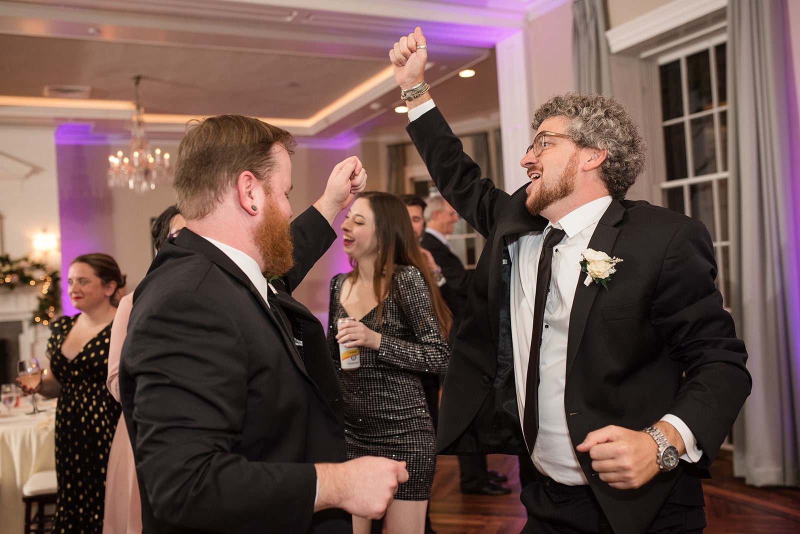two guys in dark suits dancing at wedding