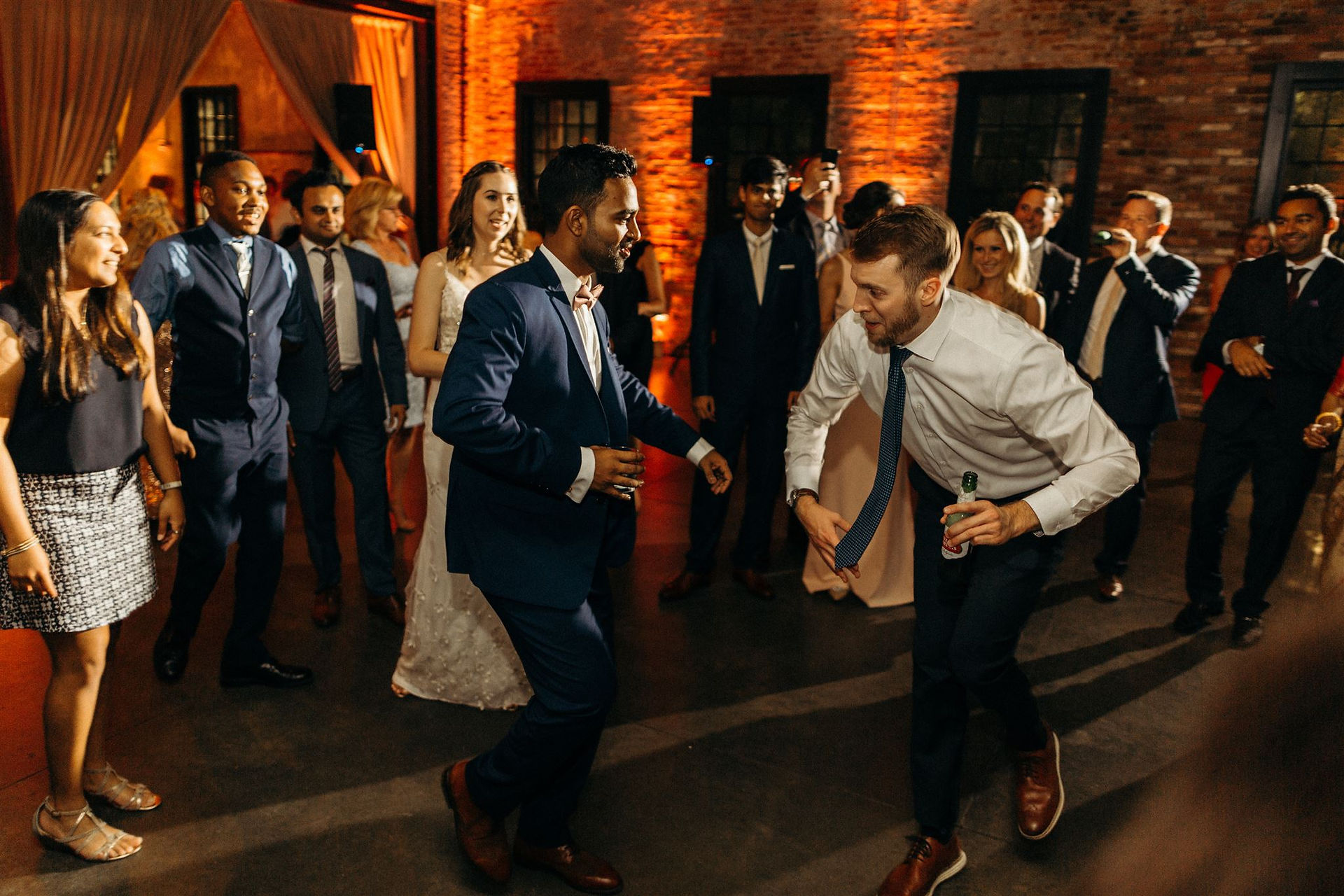 groom and friend dance while bride and guests watch