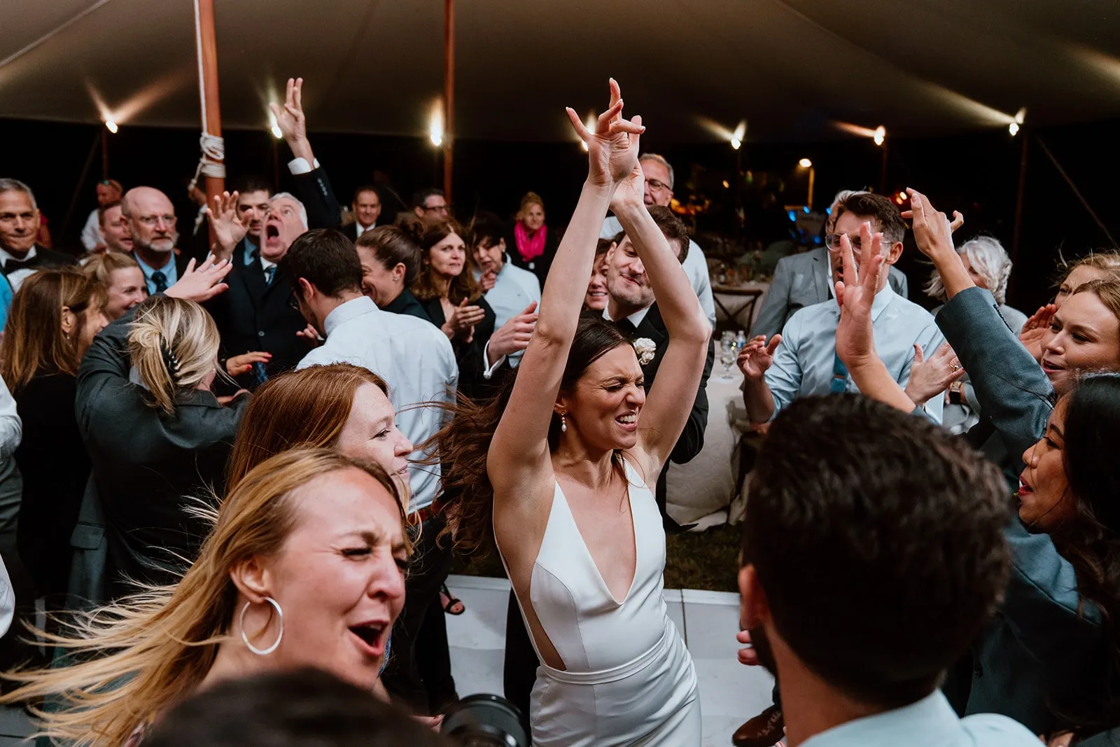 bride dancing with hands up surrounded by guests