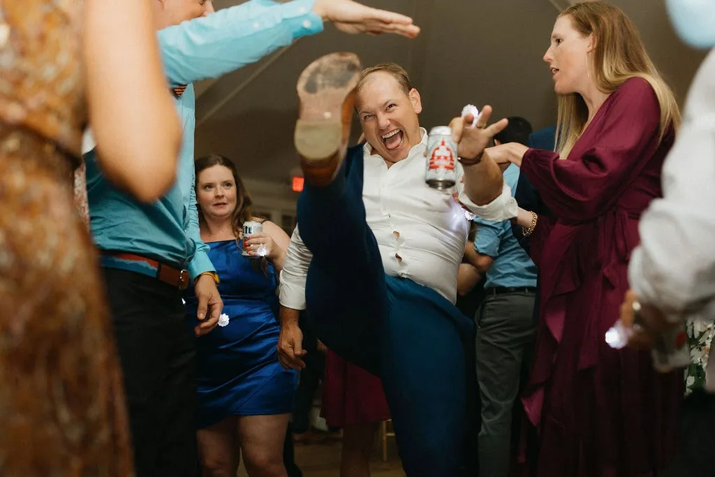 guy doing a high kick on the dance floor at a wedding
